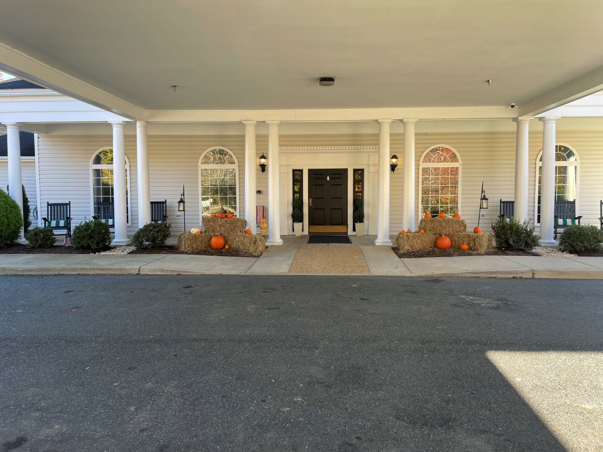 A building entrance decorated with autumn-themed elements, including pumpkins and hay bales.