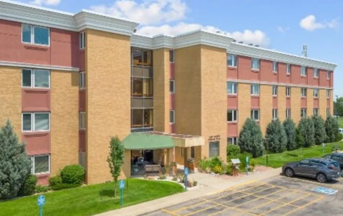 A multi-story apartment building with a landscaped entrance and clear blue skies.