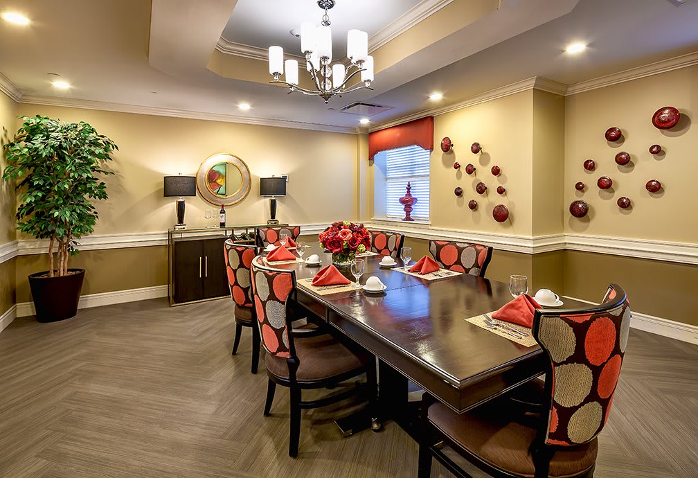 A modern dining room with a beautifully set table, featuring red and white accents and stylish wall decorations.