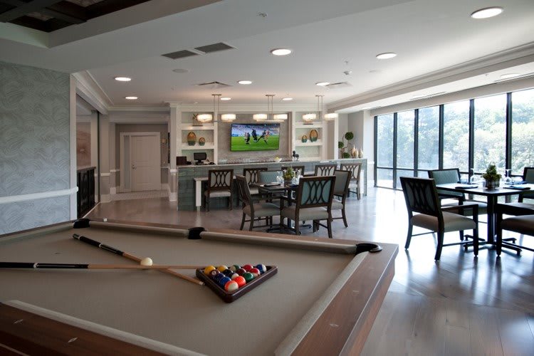 A modern game room with a billiard table, bar, and seating area.