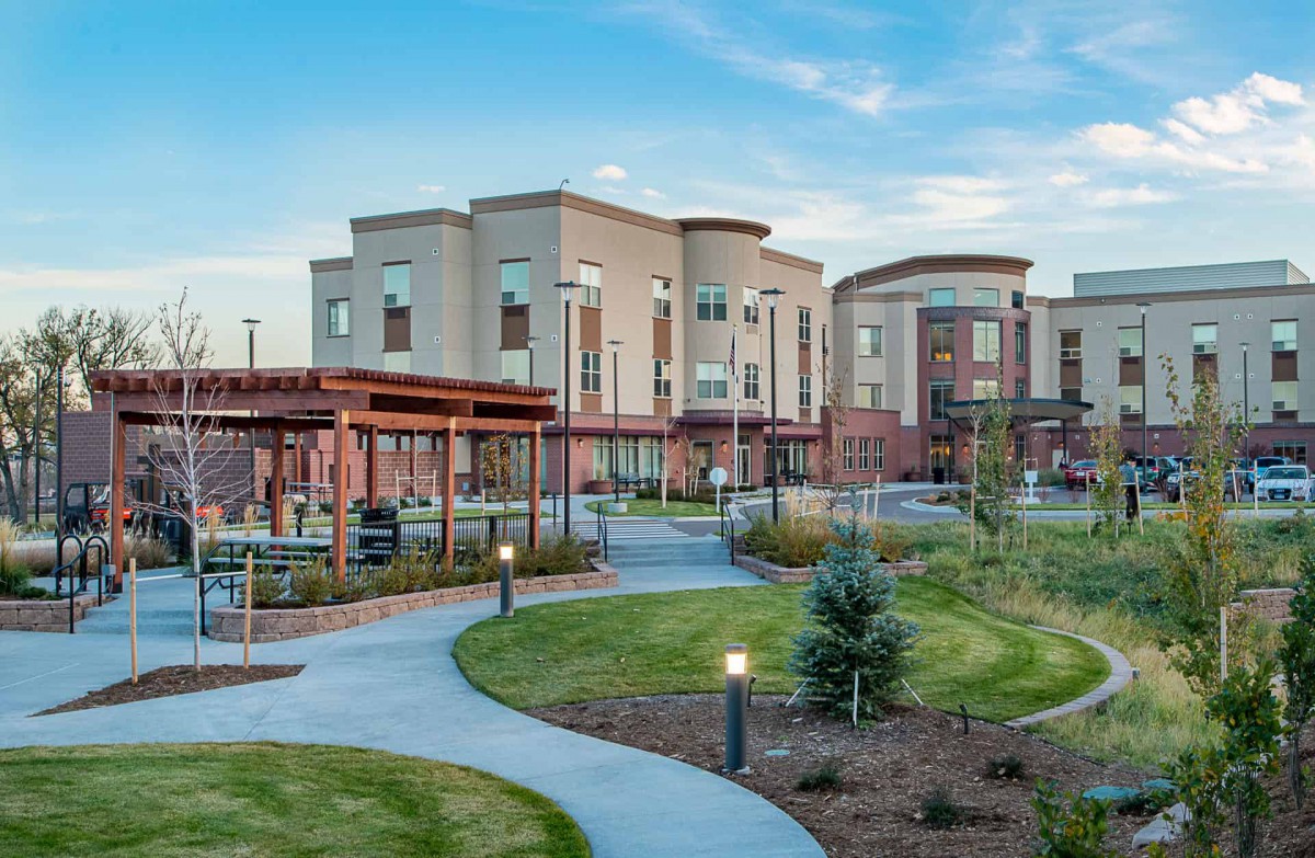A modern building with well-maintained landscaping and a winding pathway under a clear blue sky.