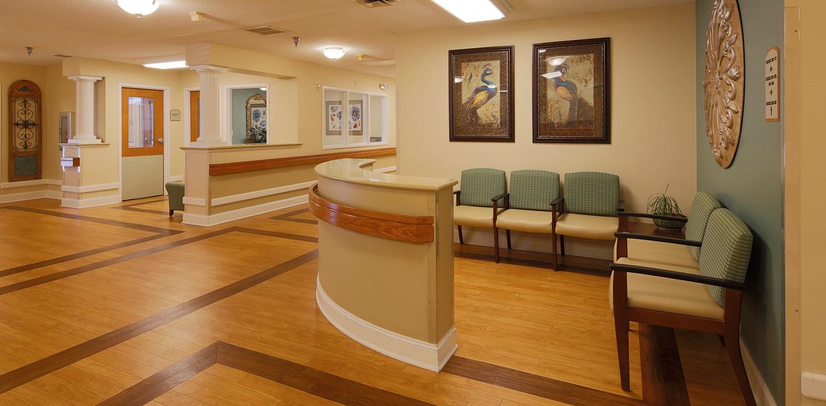 A hospital or clinic waiting room with a reception desk and chairs.