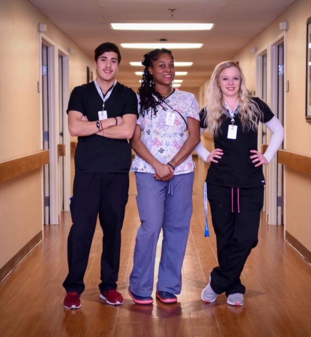 Three healthcare professionals standing together in a hospital corridor.