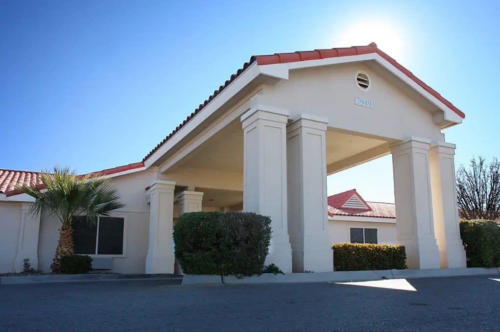 A building with a red-tiled roof and large entrance columns under a clear blue sky.