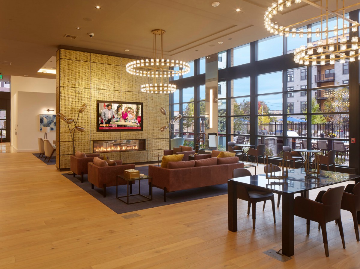 A modern lobby with comfortable seating, elegant chandeliers, and large windows.