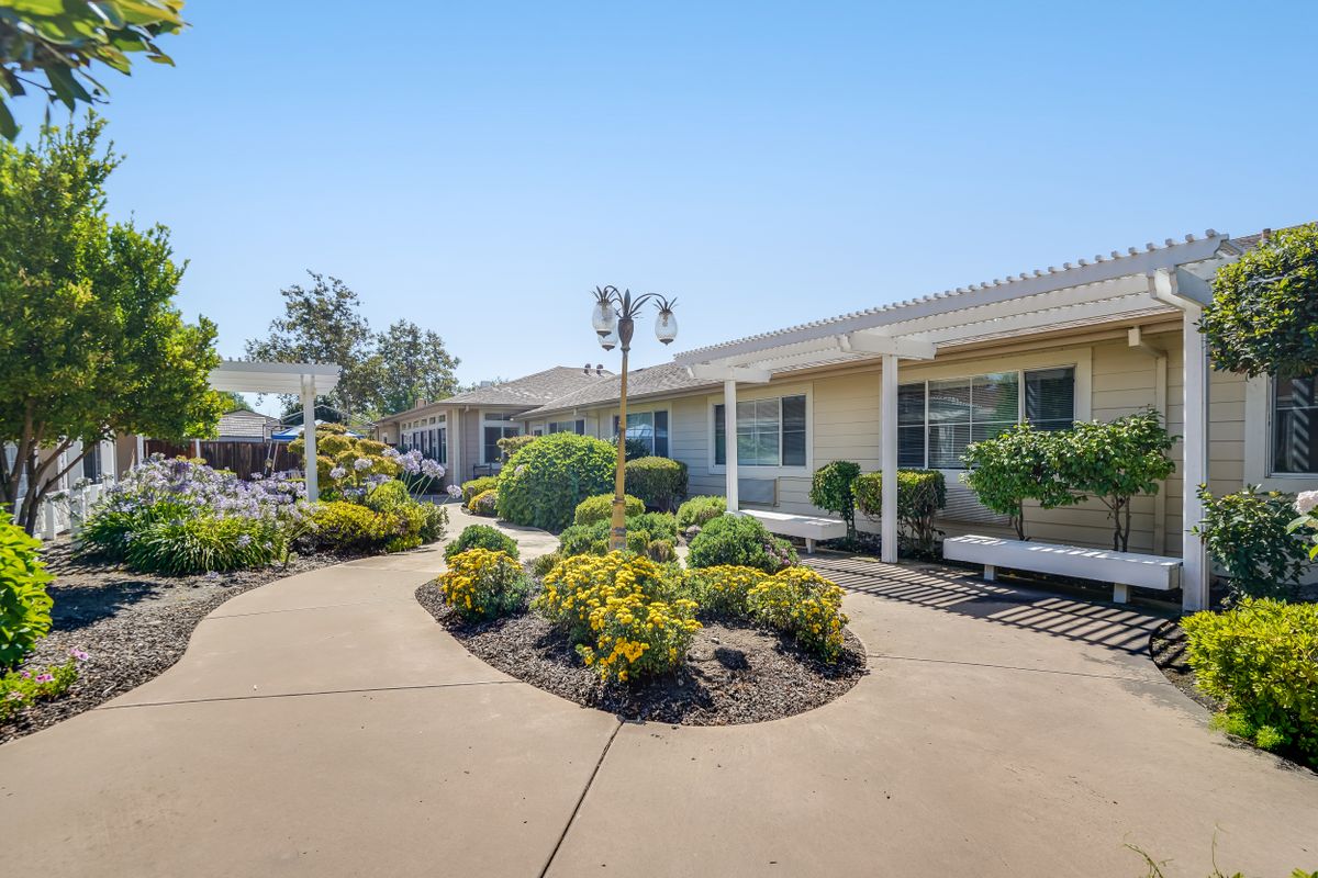A single-story building with a well-maintained pathway and landscaping under a clear blue sky.