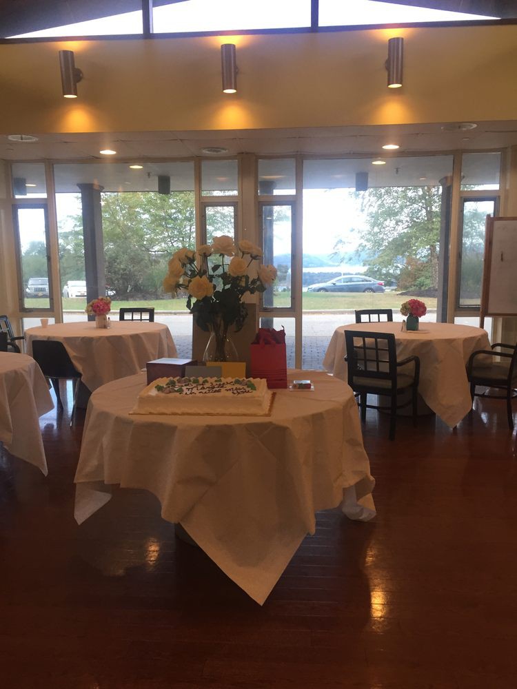 An elegantly decorated dining area prepared for an event, featuring round tables with white tablecloths and floral centerpieces.