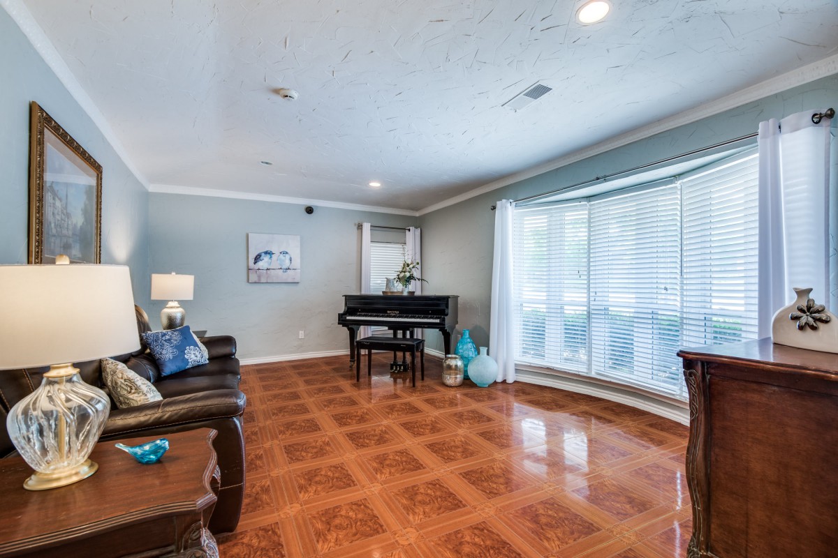 A spacious living room featuring a grand piano, hardwood floors, and comfortable seating.