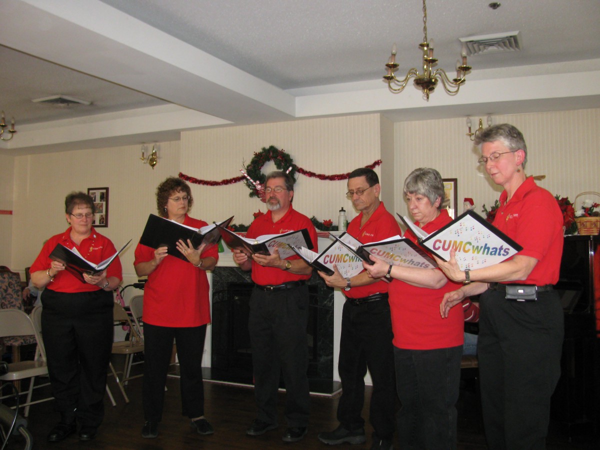 A group of people in red shirts singing together indoors.