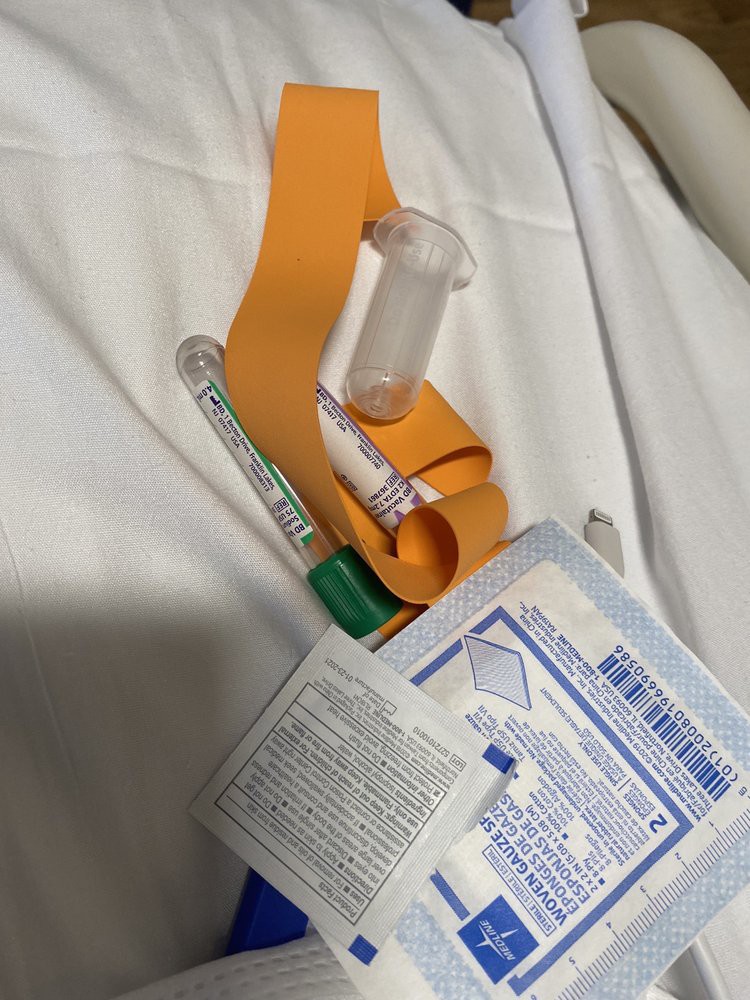 A collection of medical supplies including a bandage and syringe on a hospital sheet.