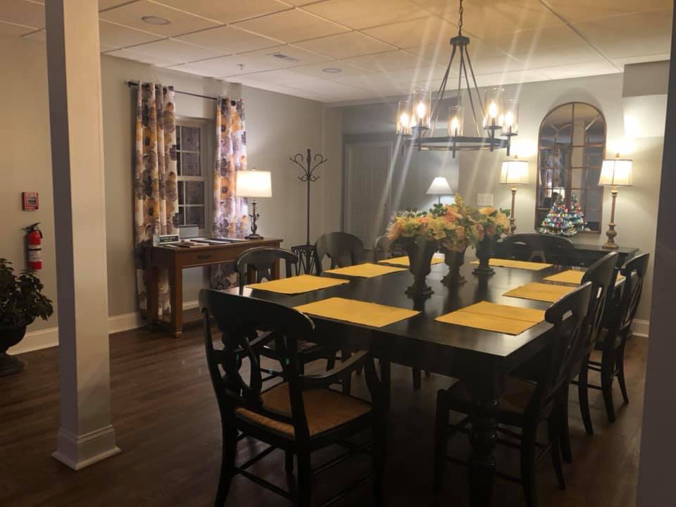 A warmly lit dining room with a large table and decorative place settings.
