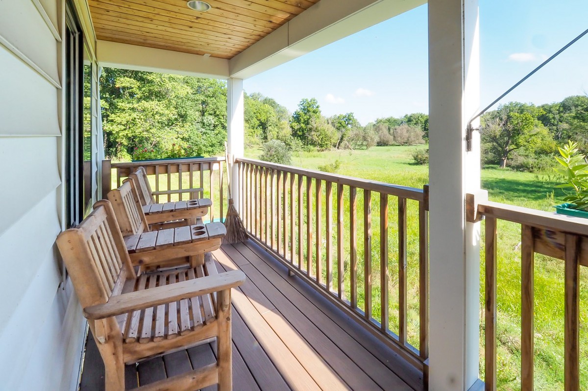 A serene porch with wooden chairs overlooking a lush green landscape.