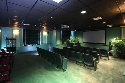 A cozy home theater setup with rows of seating and a large projector screen.