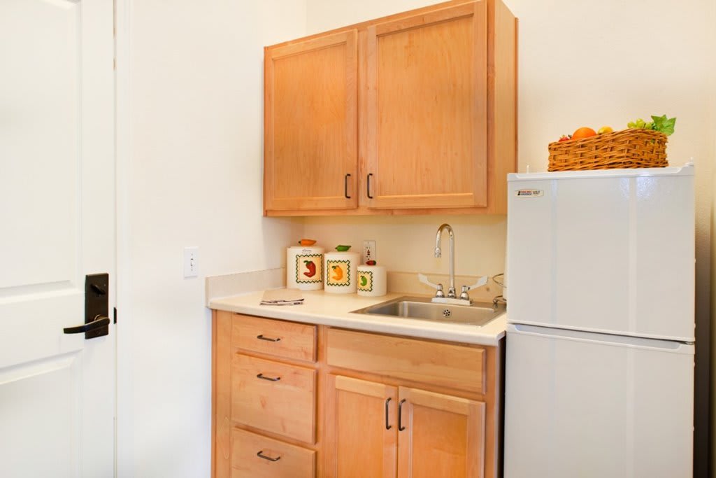 A small kitchen area with wooden cabinets, a sink, and a refrigerator.