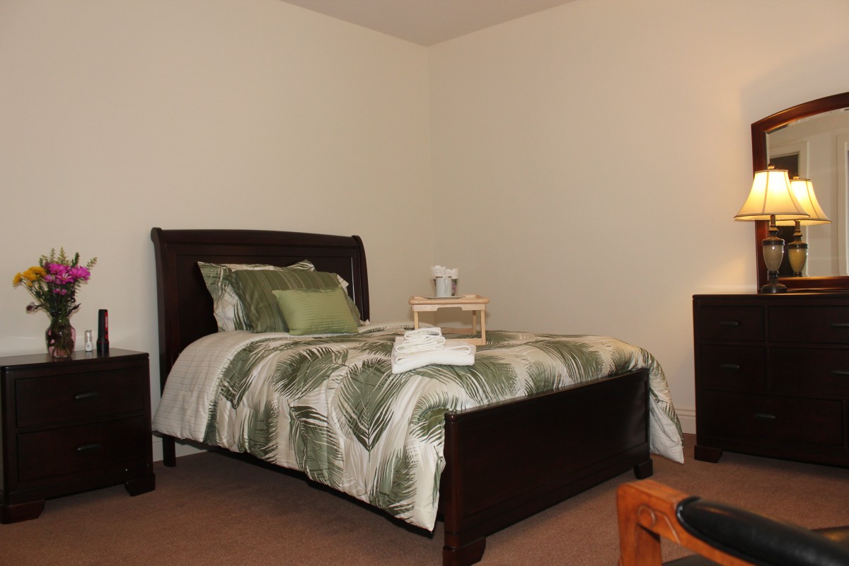 A neatly arranged bedroom with a bed and decorative bedding.