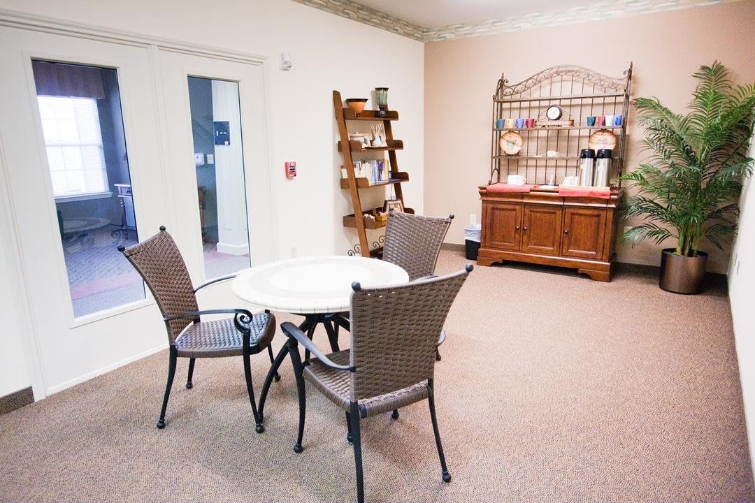 A cozy indoor seating area with a table and chairs, shelves, and decorative elements.