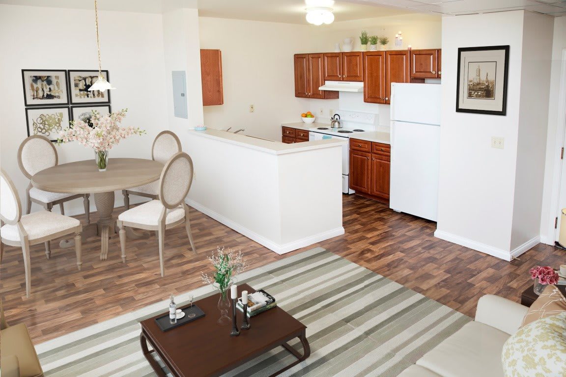 A cozy apartment interior featuring an open-plan kitchen, dining area, and living room with hardwood flooring.