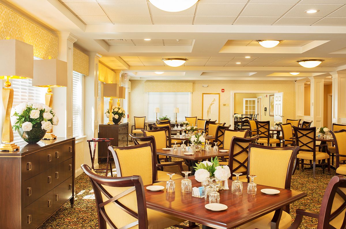 An elegant and well-lit dining room with neatly arranged tables and chairs, featuring tasteful decor.