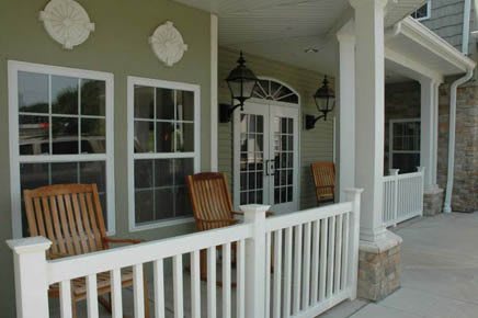 A cozy porch setup with wooden chairs and lanterns flanking French doors.