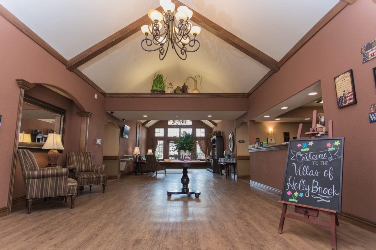 A welcoming lobby with a chandelier, wood flooring, and a seating area.