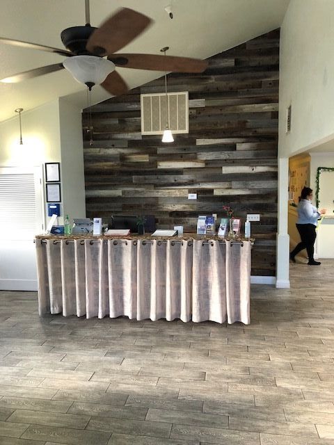 A modern office reception desk with a wooden accent wall in the background.