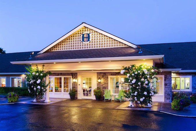 An inviting hotel exterior with warm lighting and landscaped surroundings during the evening.