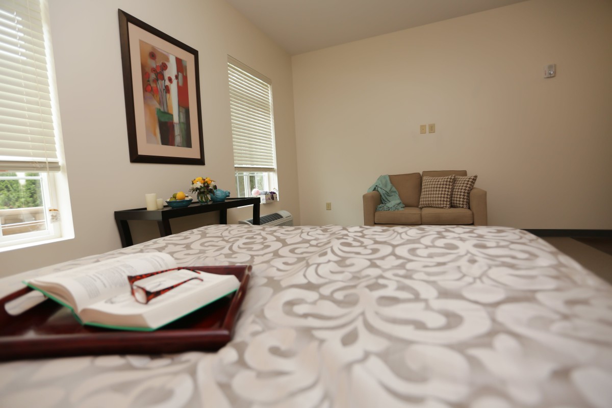 A cozy bedroom with a patterned comforter, a small sofa, and decorative artwork on the wall.