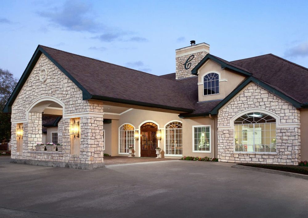 A beautiful stone-exterior house with a well-lit entrance at dusk.