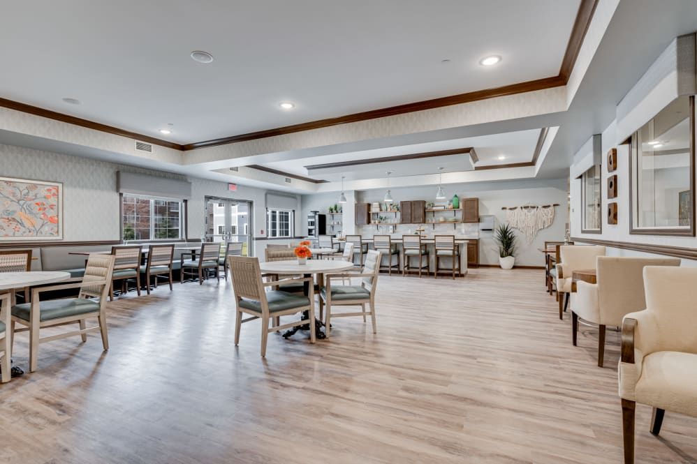 A spacious and modern dining area with wood flooring, tables, and chairs in an open layout.