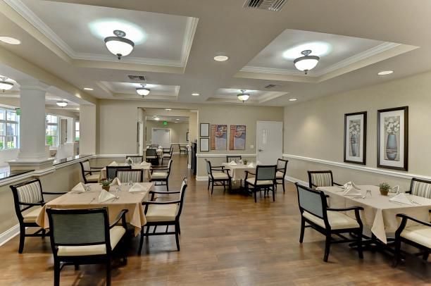 A spacious dining area with neatly arranged tables and chairs, illuminated by ceiling lights.