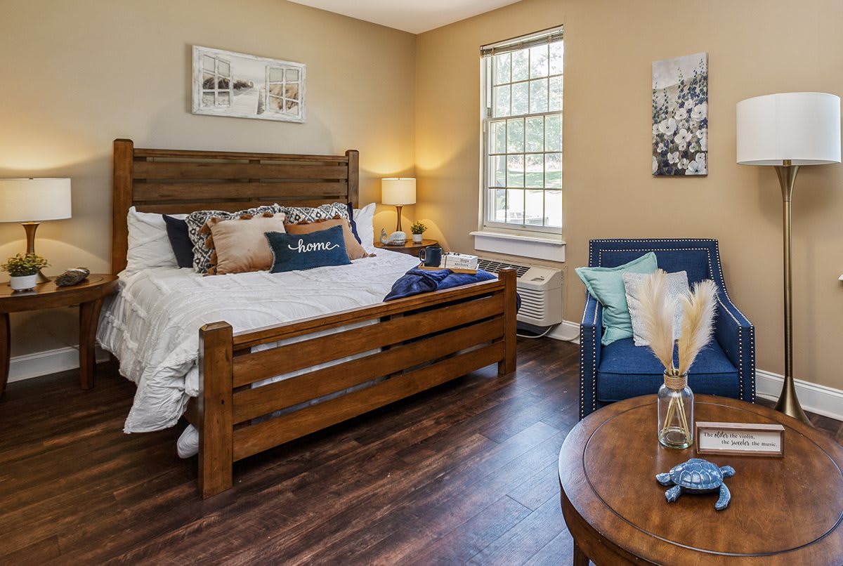 A cozy bedroom with a wooden bed frame, a comfortable blue couch, and warm lighting.