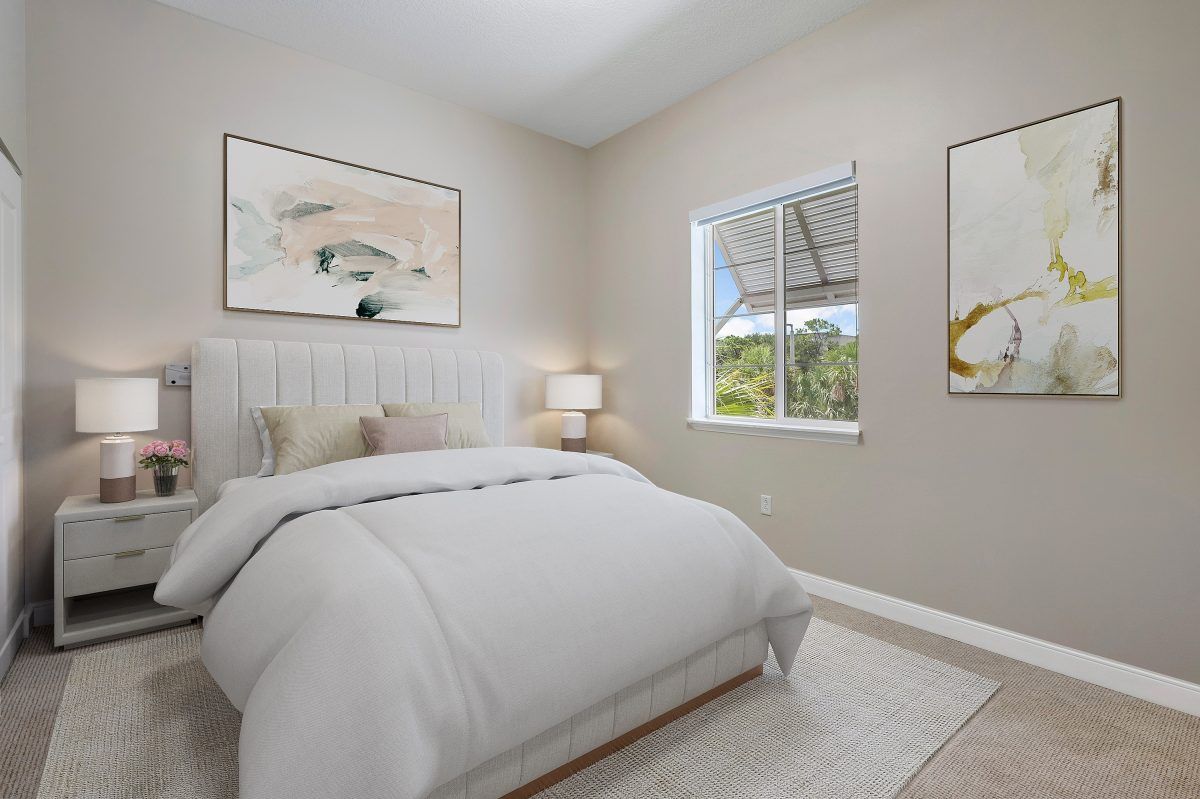 A cozy bedroom with a neatly made bed, two paintings on the walls, and natural light coming through the window.