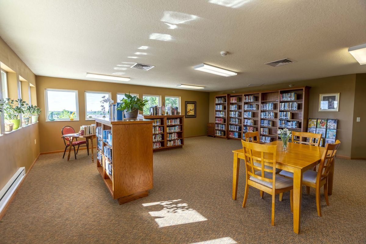 A quiet library interior with bookshelves, tables, and chairs for reading.