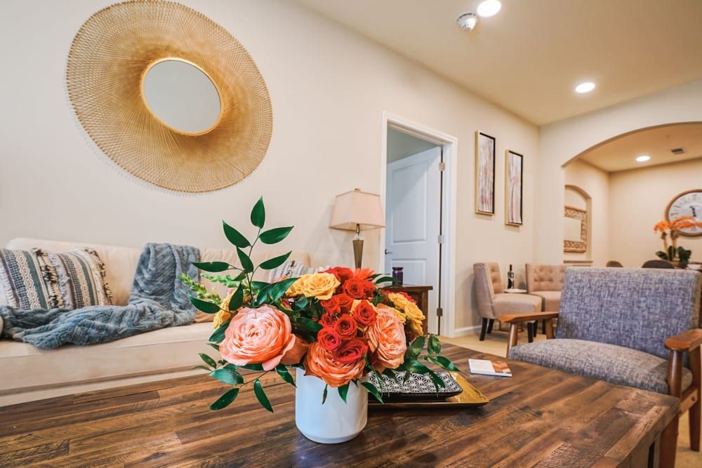 A cozy living room featuring a stylish floral arrangement on a wooden table, complemented by modern artwork and comfortable seating.
