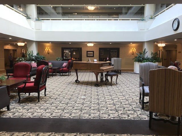 A spacious hotel lobby featuring a grand piano and comfortable seating areas.