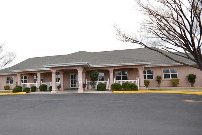 A commercial building with a parking lot in front, surrounded by trees.