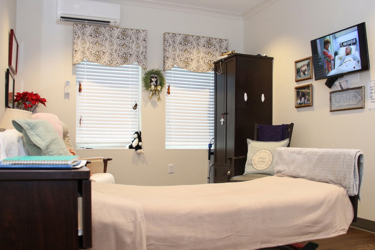 A cozy bedroom with a neatly made bed, wooden furniture, and decorated windows.