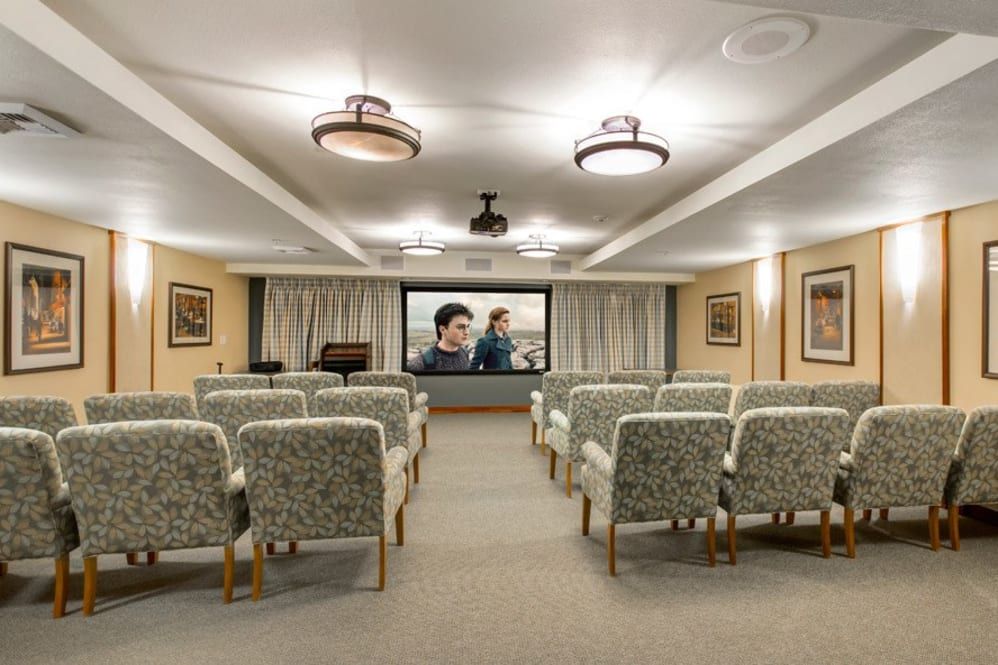 A cozy theater room with rows of chairs facing a large projector screen.