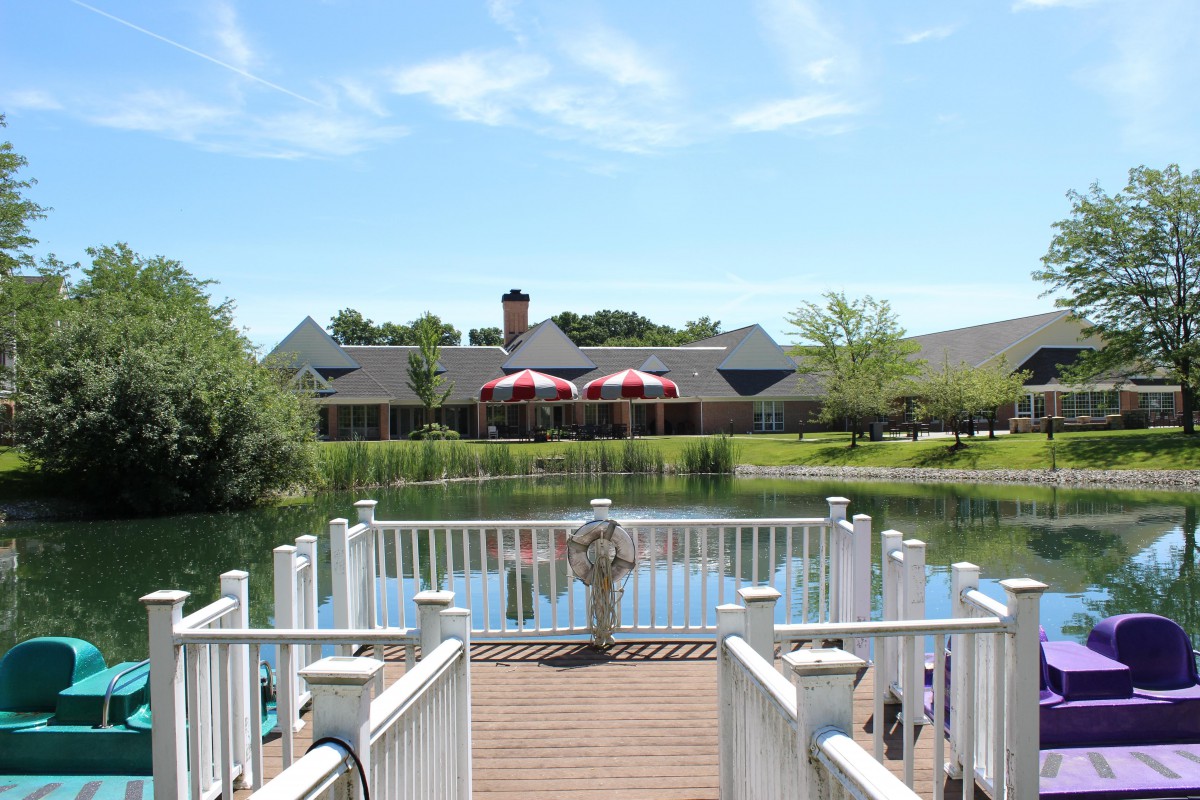 A scenic view from a dock overlooking a lake and a building in the distance on a clear day.