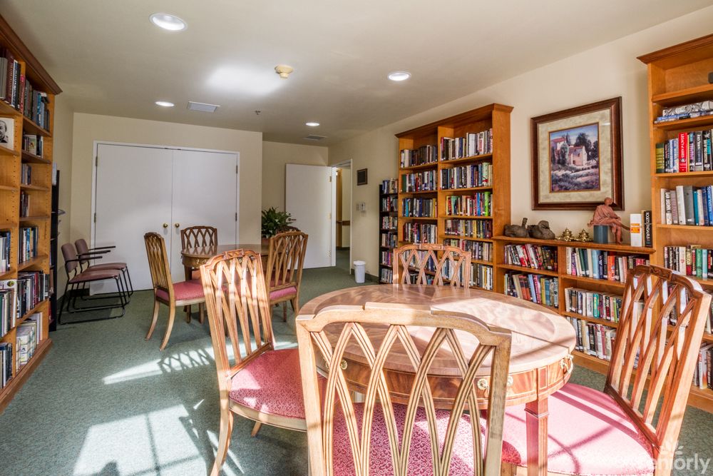 A cozy library room with bookshelves, tables, and chairs for reading.