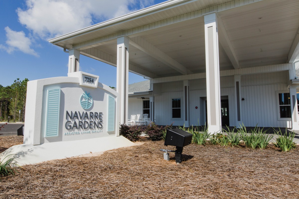 Entrance to Navarre Gardens with a welcoming sign and landscaped yard.