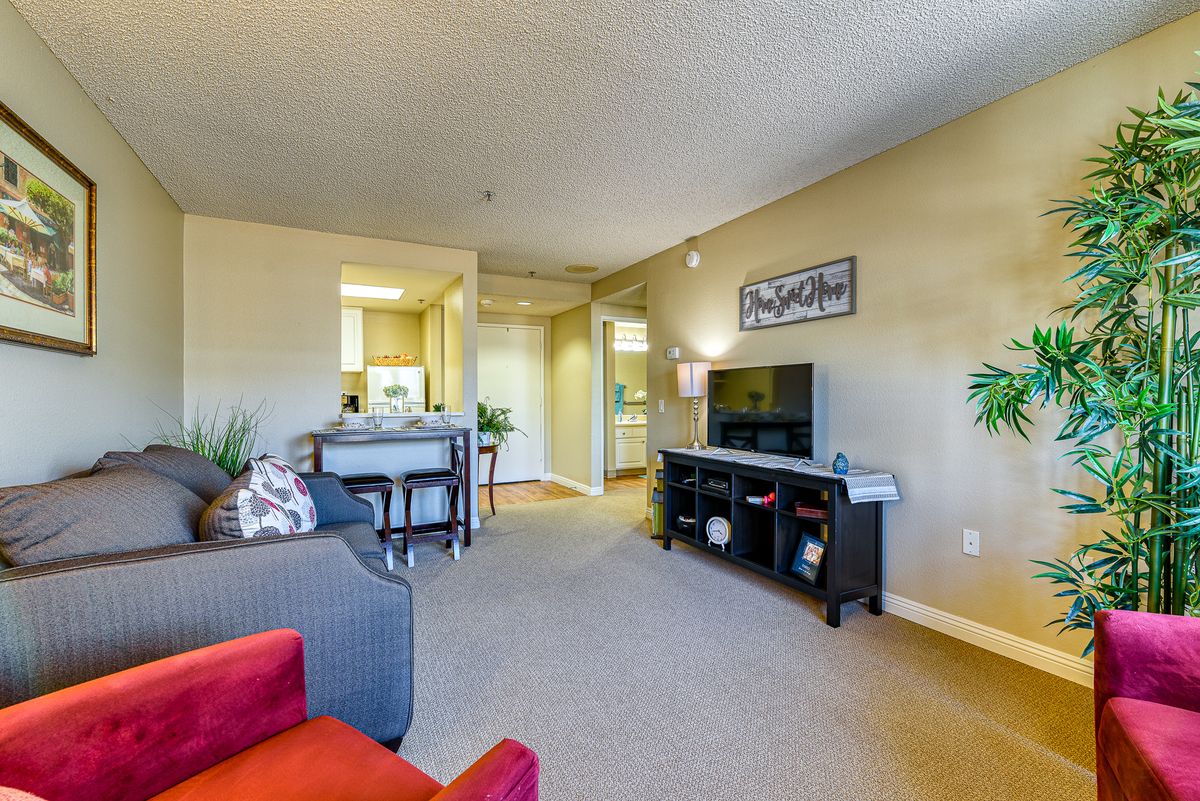 A cozy living room featuring a sofa, television stand, and dining area with warm lighting.
