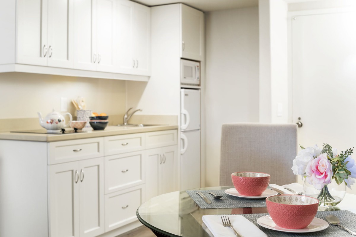 A modern kitchen with white cabinets and a cozy dining area.