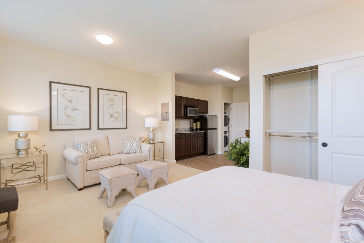 A modern studio apartment featuring a cozy living area and a compact kitchenette.