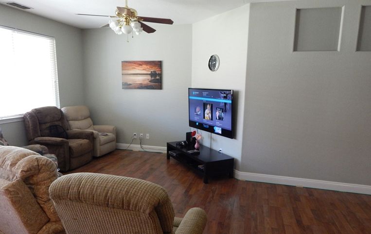 A cozy living room with recliners, a wall-mounted TV, and wooden flooring.