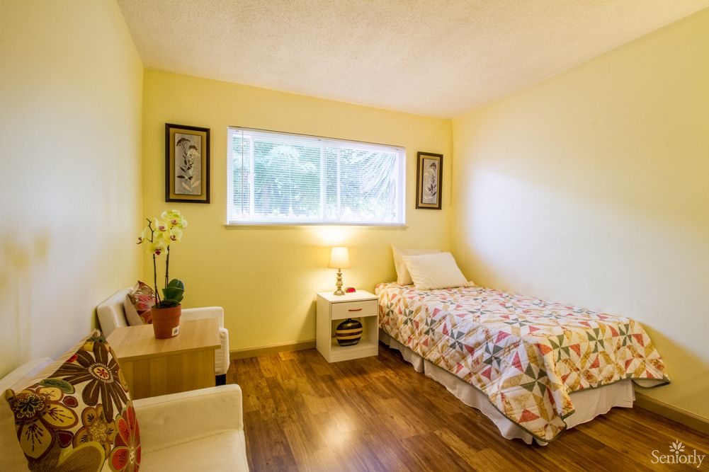 A cozy bedroom with a single bed, a lamp on the bedside table, and decorative elements.
