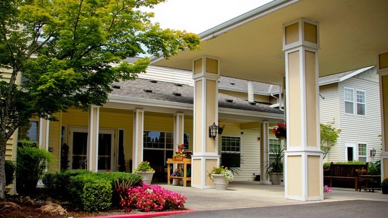 Entrance to a building with columns and landscaped surroundings.