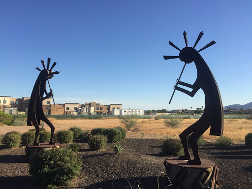 Two elegant metal sculptures of musicians playing flutes against a serene landscape.