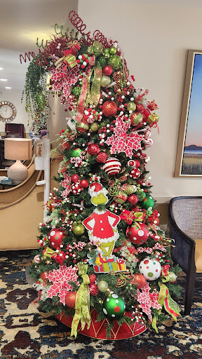 A beautifully decorated Christmas tree featuring vibrant ornaments and a playful Grinch figure.