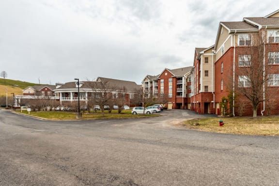 A view of a residential apartment complex with a parking lot on a cloudy day.